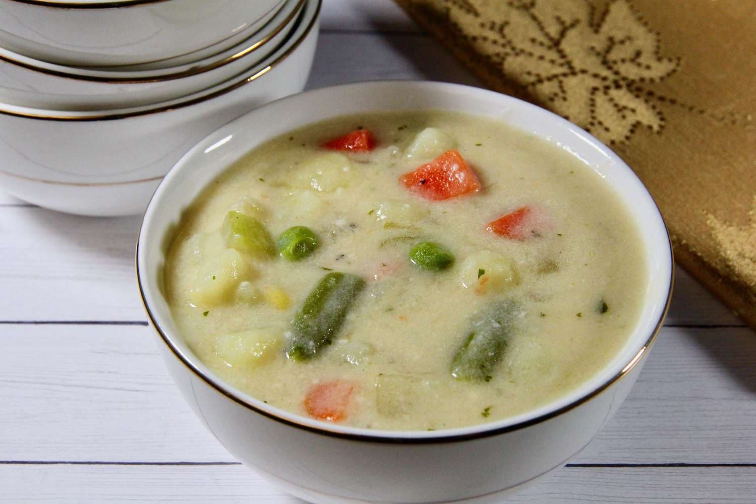 Vegetable soup on a white plate with a golden border